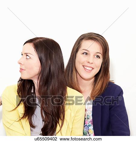 Stock Image - Young women looking away against white background. Fotosearch