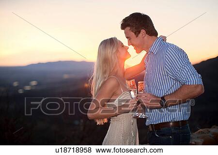 Affectionate couple having champagne outdoors at sunset View Large Photo Image Stock Photo - Affectionate couple having champagne outdoors at sunset. Fotosearch