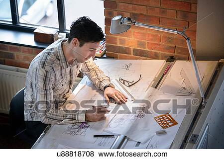 Stock Photo - Architect drawing plans at drawing board. Fotosearch
