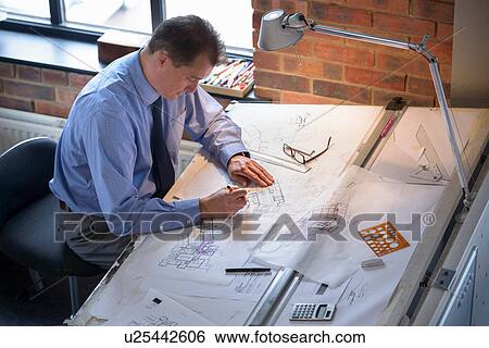 Architect drawing plans at drawing board View Large Photo Image Stock Photograph - Architect drawing plans at drawing board. Fotosearch