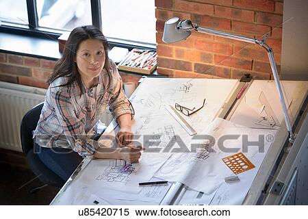 Stock Photography - Architect drawing plans at drawing board, portrait. Fotosearch