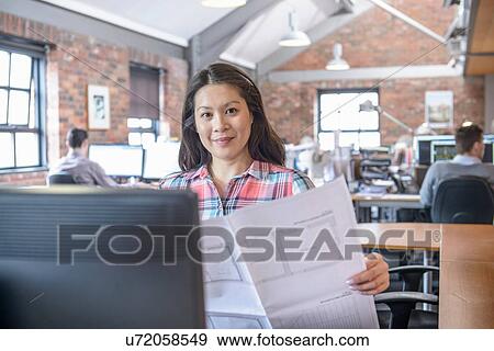 Architect holding plans at desk in office View Large Photo Image Stock Photo - Architect holding plans at desk in office. Fotosearch
