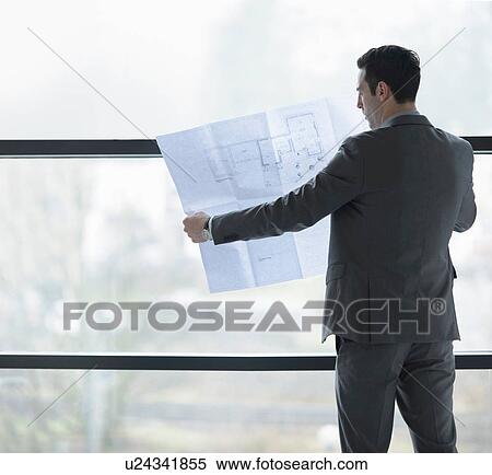Architect inspecting plans by office window View Large Photo Image Stock Photography - Architect inspecting plans by office window. Fotosearch
