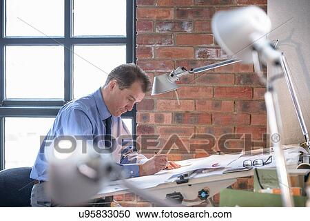 Architect making plans at drawing board View Large Photo Image Stock Image - Architect making plans at drawing board. Fotosearch