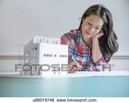 Stock Photo - Architect working next to model building. Fotosearch
