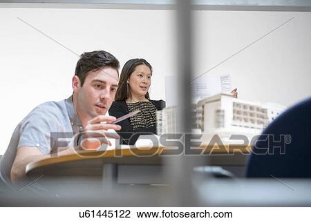 Stock Image - Architects making presentation in boardroom with scale model. Fotosearch