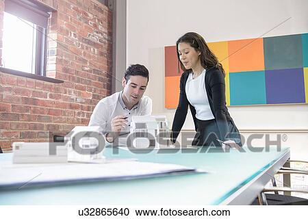 Architects working together on model of building in office View Large Photo Image Stock Image - Architects working together on model of building in office. Fotosearch