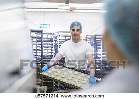 Baker holding tray of prepared dough ready for the oven View Large Photo Image Picture - Baker holding tray of prepared dough ready for the oven. Fotosearch