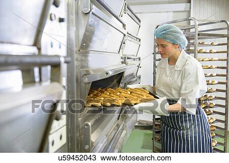 Baker removing tray of baked pastries from oven in bakery View Large Photo Image Stock Image - Baker removing tray of baked pastries from oven in bakery. Fotosearch