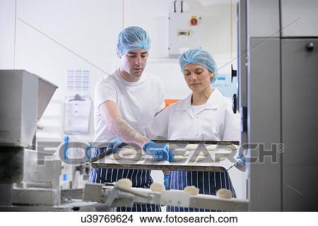 Bakers arranging dough on tray View Large Photo Image Picture - Bakers arranging dough on tray. Fotosearch