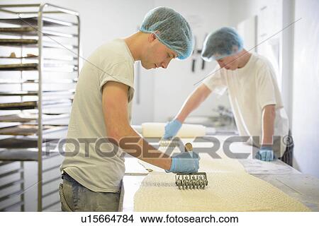 Bakers in protective clothing preparing length of dough View Large Photo Image Picture - Bakers in protective clothing preparing length of dough. Fotosearch