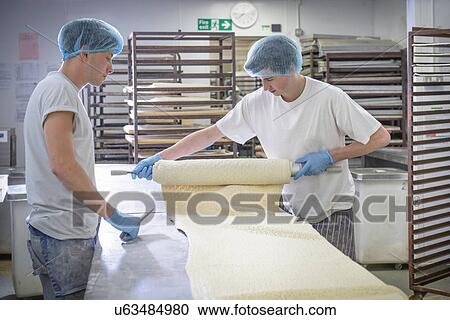 Bakers in protective clothing preparing length of dough View Large Photo Image Stock Image - Bakers in protective clothing preparing length of dough. Fotosearch