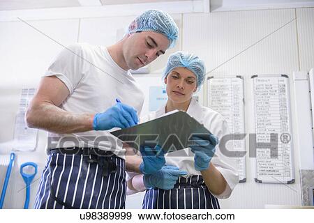 Stock Photo - Bakers looking at checklist on clipboard. Fotosearch