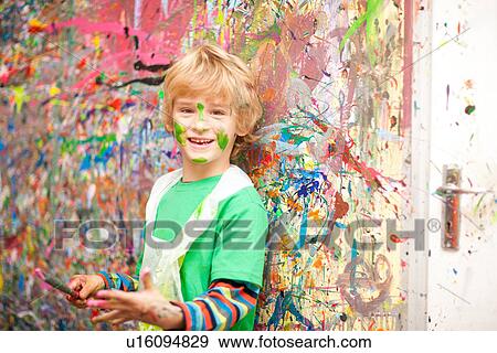Stock Photo - Boy in front of paint-splattered wall. Fotosearch