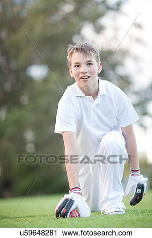 Stock Image - Boy kneeling on cricket pitch. Fotosearch