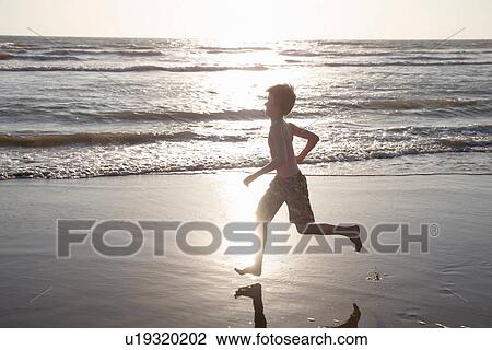 Boy running along beach in sunlight View Large Photo Image Stock Image - Boy running along beach in sunlight. Fotosearch