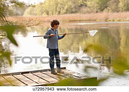 Stock Image - Boy standing on pier and fishing in river. Fotosearch