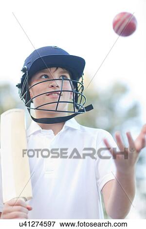 Stock Photo - Boy wearing helmet catching cricket ball. Fotosearch