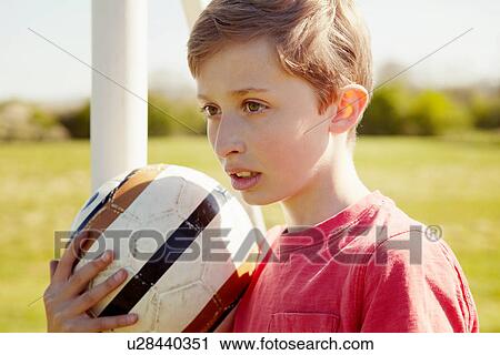 Stock Image - Boy with ball looking into the distance. Fotosearch