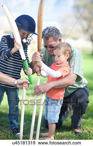 Stock Photo - Boys and grandfather preparing stumps for cricket. Fotosearch