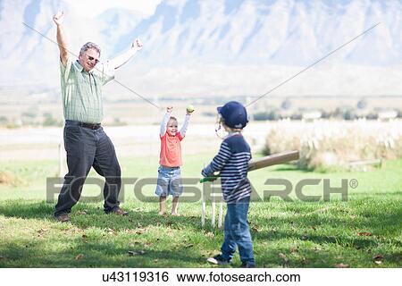Stock Photograph - Boys grandfather playing cricket. Fotosearch