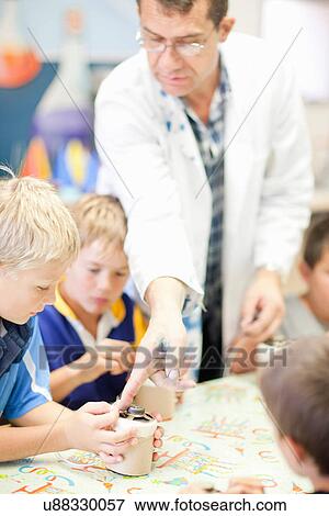 Stock Photo - Boys making craft object with supervisor. Fotosearch