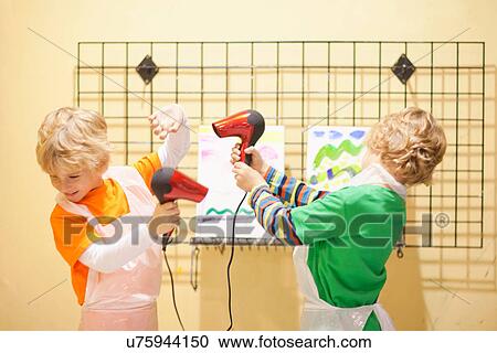 Boys playing with hair dryers whilst drying their paintings View Large Photo Image Stock Image - Boys playing with hair dryers whilst drying their paintings. Fotosearch