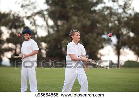 Stock Photograph - Boys practising hitting cricket ball with bat. Fotosearch