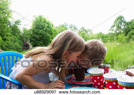 Brother and sister competing for cake at picnic table View Large Photo Image Stock Photo - Brother and sister competing for cake at picnic table. Fotosearch