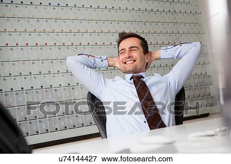 Stock Photo - Businessman leaning back in chair with arms behind head. Fotosearch