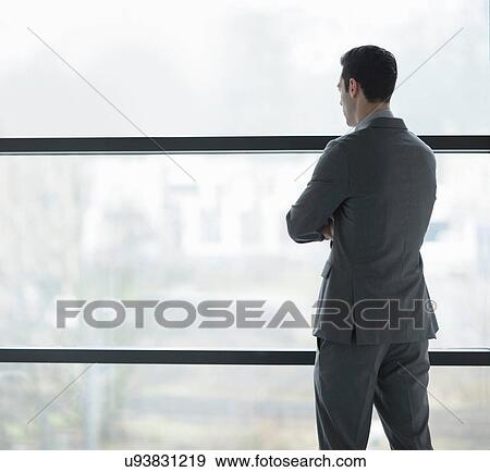 Stock Photo - Businessman looking through window. Fotosearch