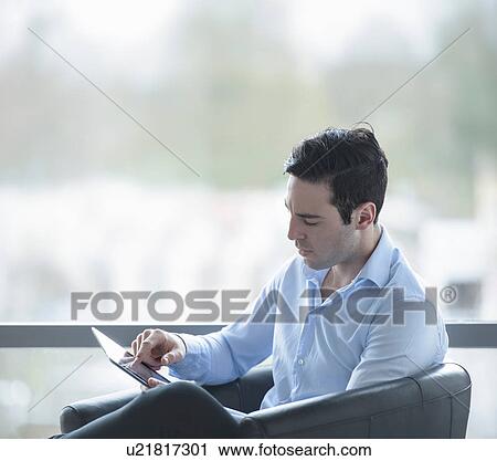 Stock Image - Businessman using digital tablet by window of office. Fotosearch
