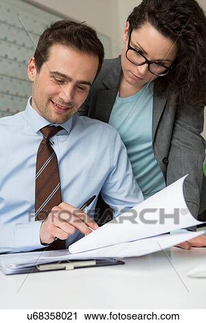 Businesspeople smiling looking at paperwork View Large Photo Image Stock Image - Businesspeople smiling looking at paperwork. Fotosearch