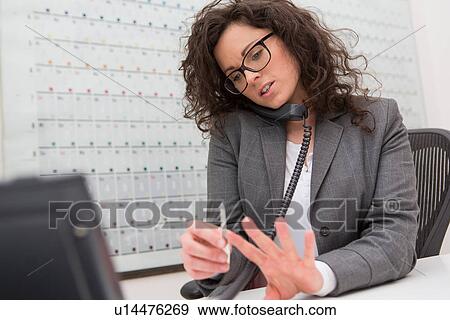 Stock Photo - Businesswoman on telephone call, filing her fingernails. Fotosearch