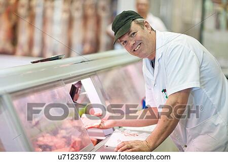 Butcher choosing meat from cabinet View Large Photo Image Stock Photo - Butcher choosing meat from cabinet. Fotosearch