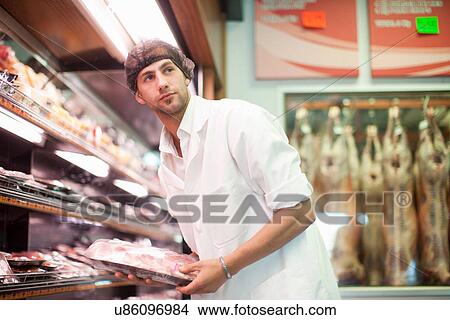 Picture - Butcher holding packet of meat in butcher's shop. Fotosearch