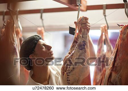 Stock Image - Butcher inspecting meat. Fotosearch