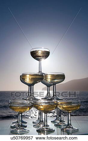 Champagne glasses in pyramid shape with sea in background View Large Photo Image Stock Photo - Champagne glasses in pyramid shape with sea in background. Fotosearch