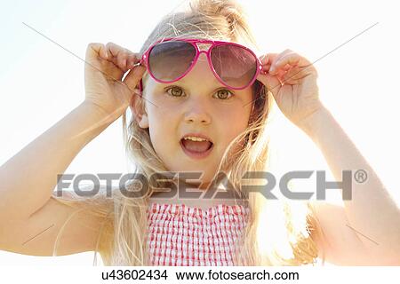 Picture - Child putting on sun glasses on hot sunny day. Fotosearch