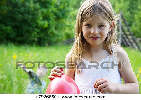 Stock Image - Close portrait of young girl holding red balloon. Fotosearch