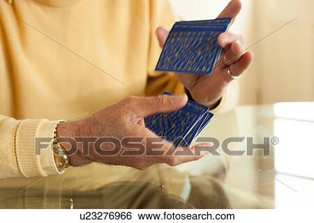 Stock Photograph - Close up of aged hands shuffling playing cards. Fotosearch