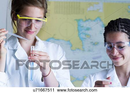 Stock Image - Close up of teenage girls with pipettes and test tube. Fotosearch
