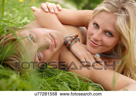 Close up of young couple lying on grass looking toward camera View Large Photo Image Stock Photo - Close up of young couple lying on grass looking toward camera. Fotosearch