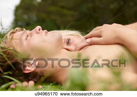 Close up of young couple lying together on grass View Large Photo Image Stock Image - Close up of young couple lying together on grass. Fotosearch