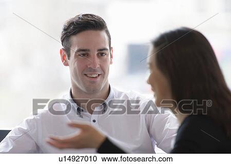 Stock Image - Colleagues conducting business meeting in front of window. Fotosearch