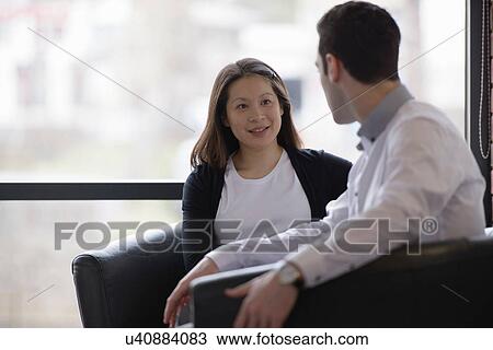Colleagues conducting business meeting in front of window View Large Photo Image Stock Image - Colleagues conducting business meeting in front of window. Fotosearch