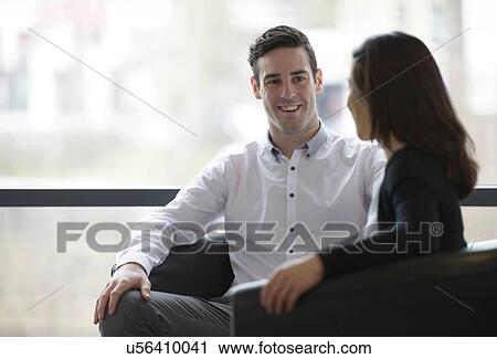 Stock Image - Colleagues conducting business meeting in front of window. Fotosearch
