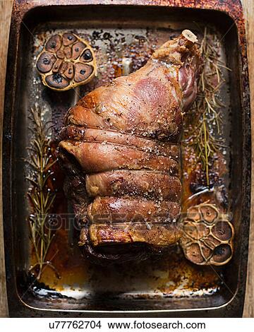 Picture - Cooked leg of lamb in roasting tin. Fotosearch