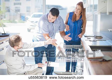 Couple and salesman looking at dishwasher in kitchen showroom View Large Photo Image Stock Photo - Couple and salesman looking at dishwasher in kitchen showroom. Fotosearch