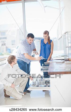 Couple and salesman looking at dishwasher in kitchen showroom View Large Photo Image Stock Photography - Couple and salesman looking at dishwasher in kitchen showroom. Fotosearch